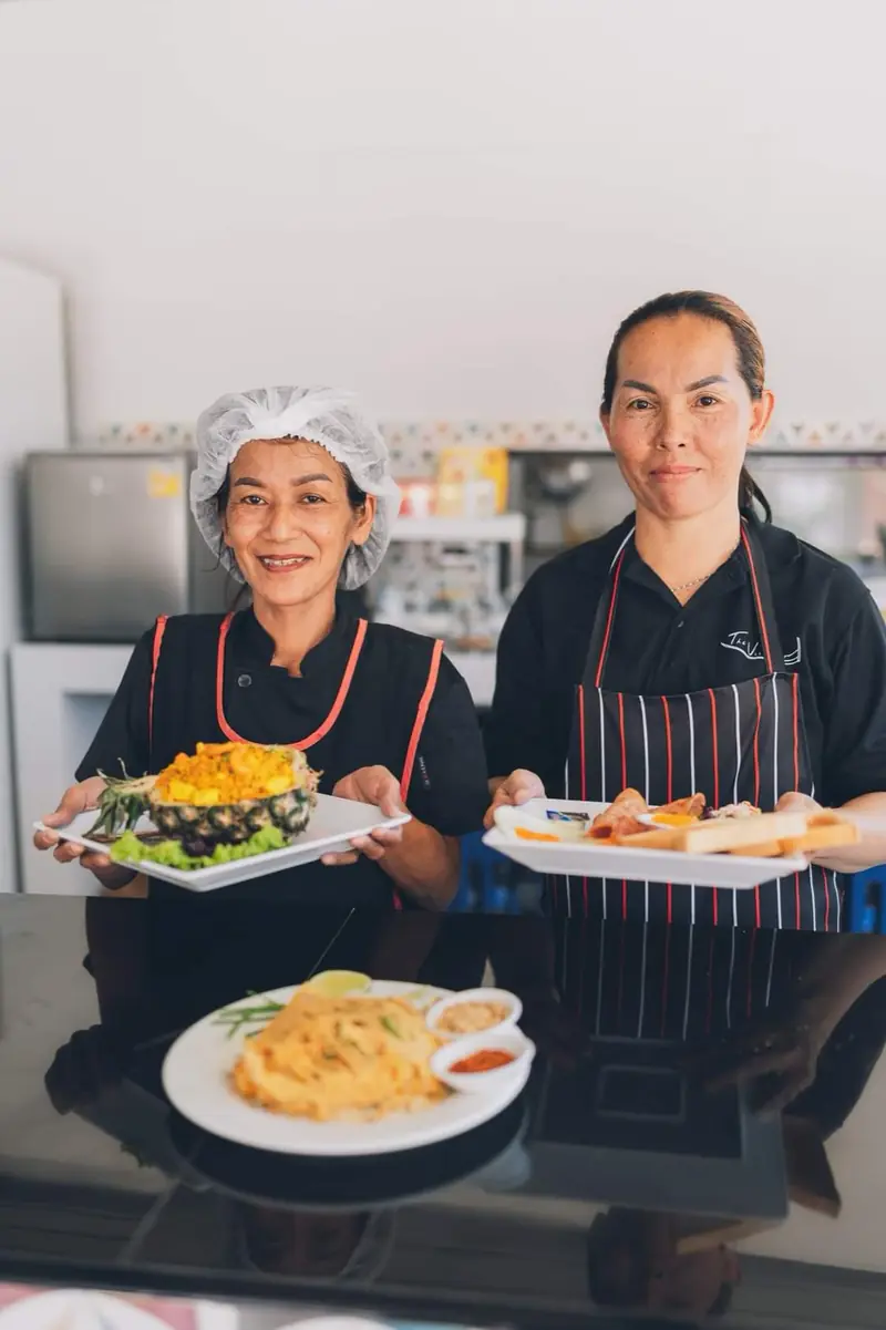The smiling Villager Café team with dishes from the kitchen