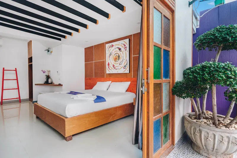 A king bed seen through open wooden doors beside the courtyard pool