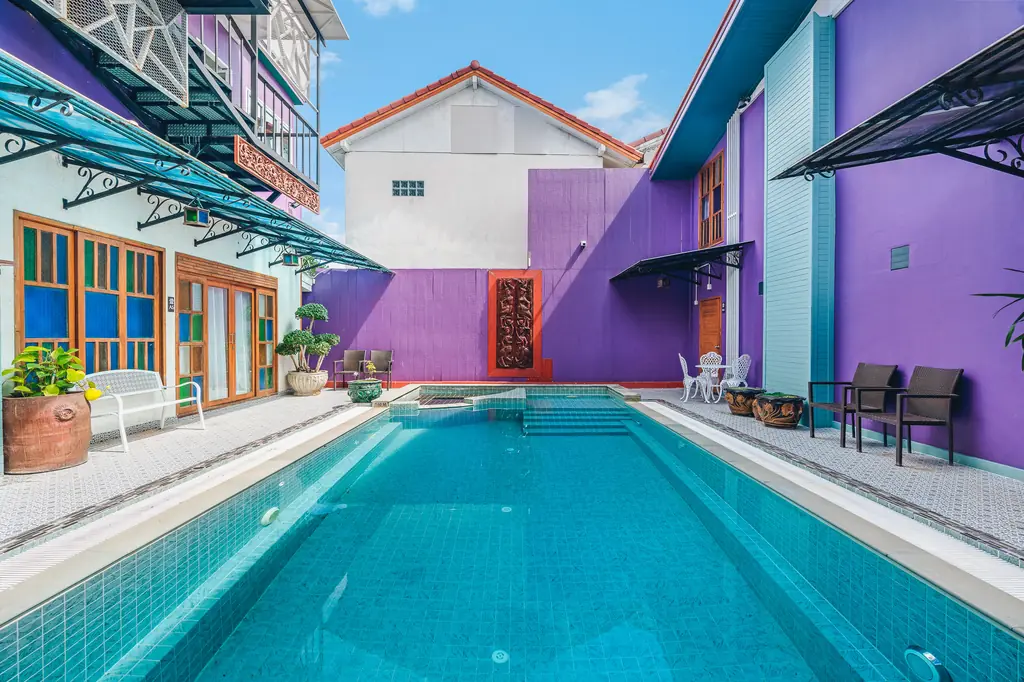 The turquoise courtyard pool with purple walls and wooden doors at The Villager Samui